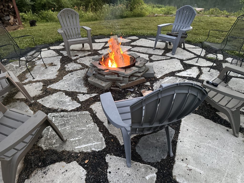 Outdoor stone patio with chairs around a fire pit
