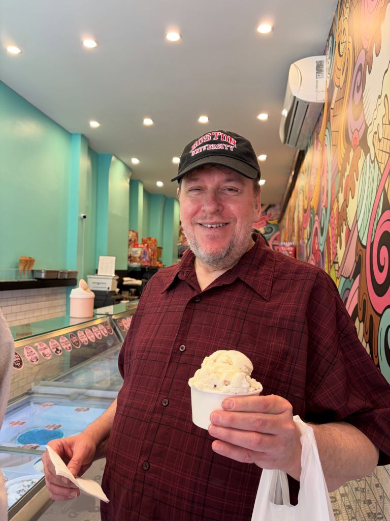A member smiling and holding a cup of ice cream during a birthday outing