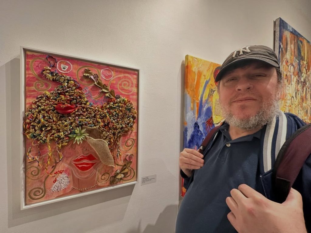 A member standing beside colorful artwork at Fountain House Gallery